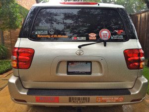 A silver suv with many stickers on the back of it.