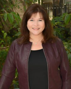 A woman in a black shirt and brown jacket