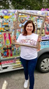 A woman holding up two large frames in front of her face.