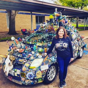 A woman standing next to a car covered in many different items.