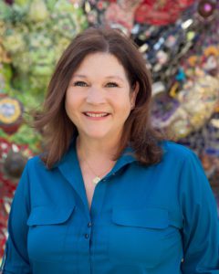 A woman in blue shirt smiling for the camera.