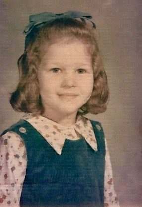 A young girl in a blue dress and white shirt.