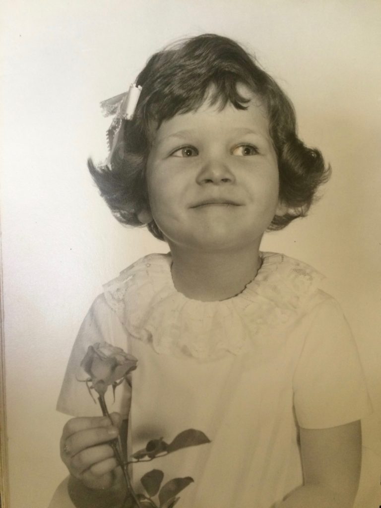 A young girl holding a flower in her hand.