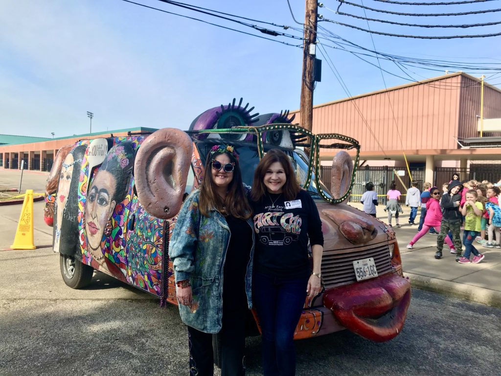 Two women standing next to a colorful van.